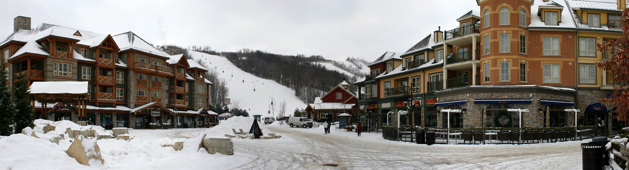 Panorama of Blue Mountain Village under fresh snow, with lodges on both sides and a ski run rising behind