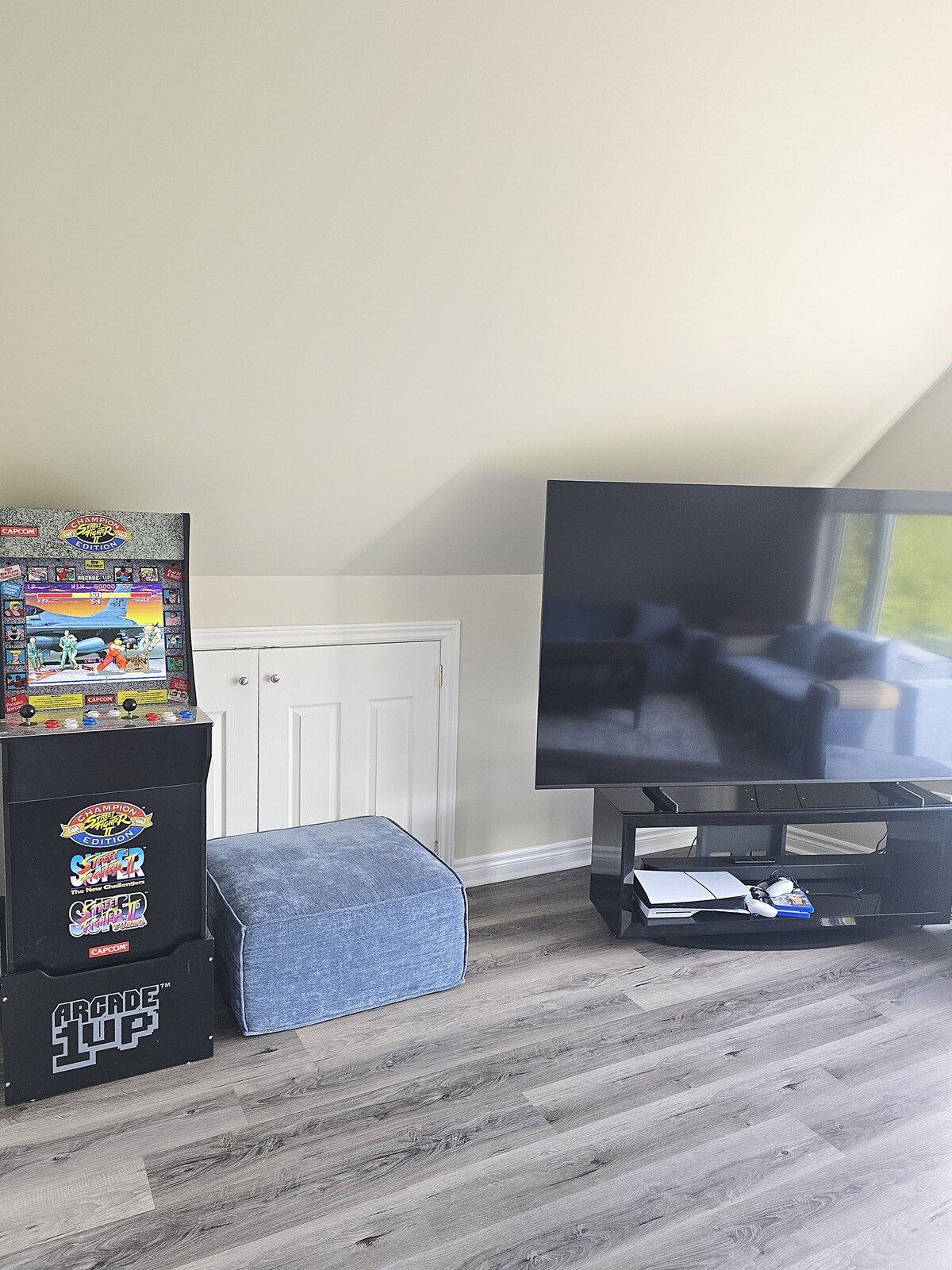 A retro arcade cabinet and a TV in a corner of the loft
