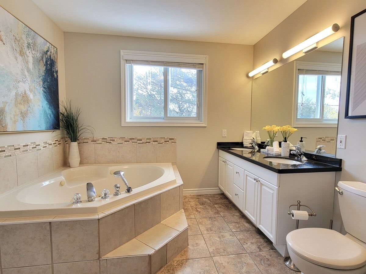 Bright bathroom with a corner jetted tub, a vanity and a glass shower