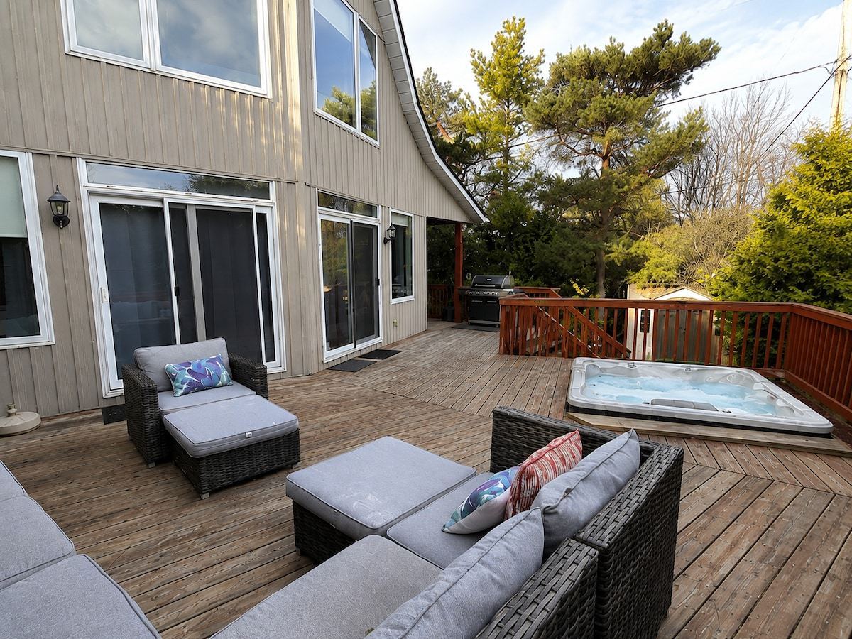 Wicker lounge seating and the hot tub on the deck at the back of the chalet