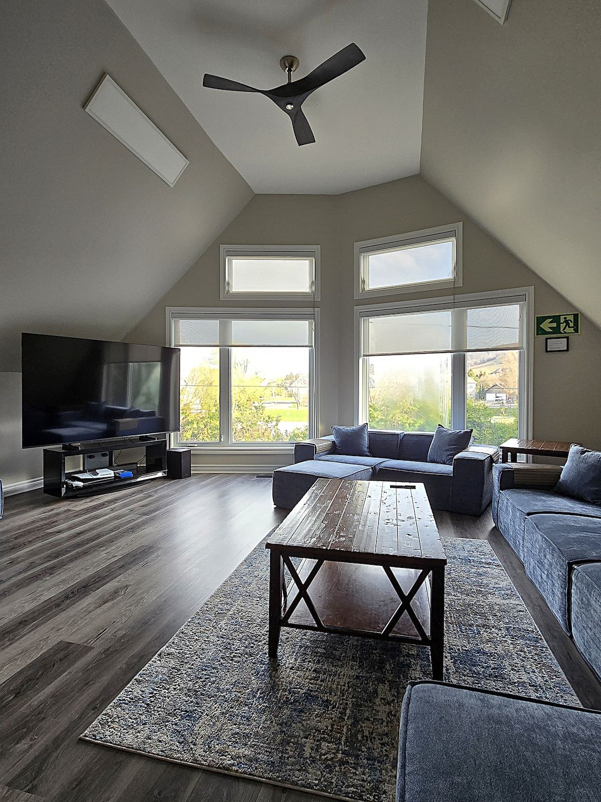 Loft living room under a peaked ceiling, with a big sectional, coffee table and tall windows