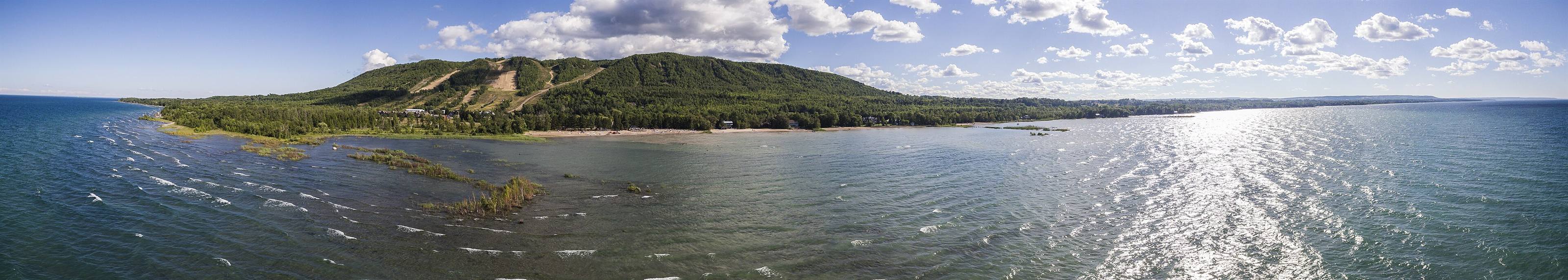 Georgian Bay sparkling in the sun, with a sandy point and the green escarpment rising behind