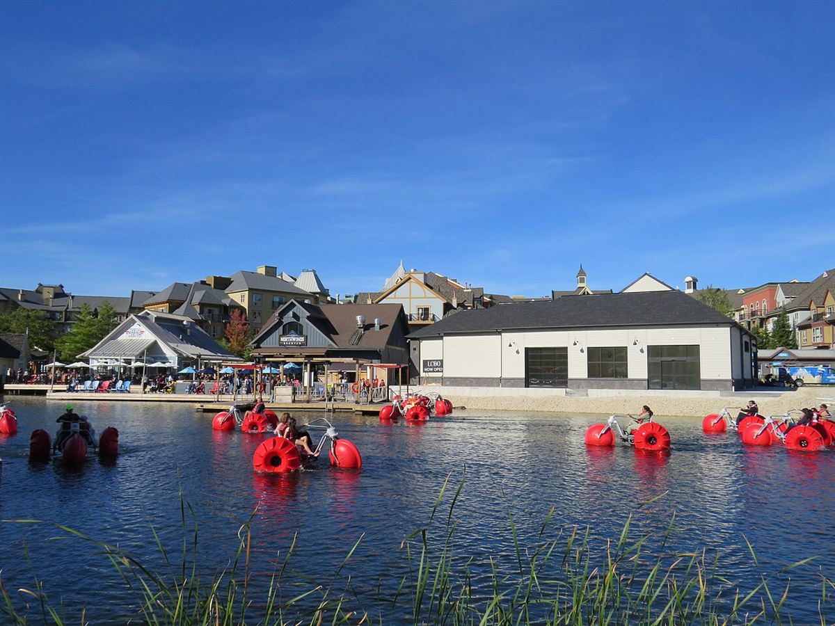 Red water bikes on the Mill Pond in early October, in front of the Village under a blue sky