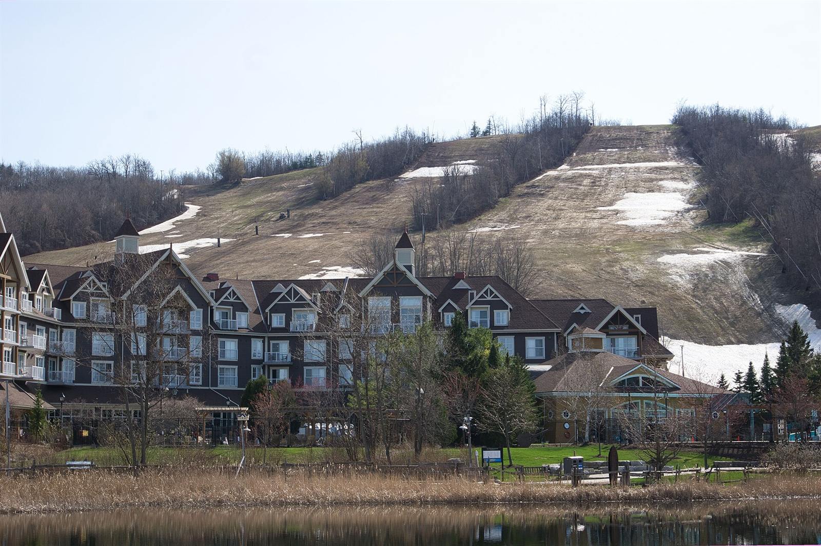 Village lodges beside the pond in April, with the last patches of snow on the ski runs above